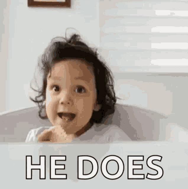 a baby is sitting in a bathtub with the words `` he does '' written on the side .