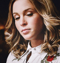 a close up of a woman wearing a white shirt with a red rose on it