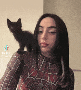 a woman in a spiderman costume has a black cat on her shoulder ..
