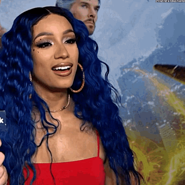 a woman with blue hair and hoop earrings is smiling