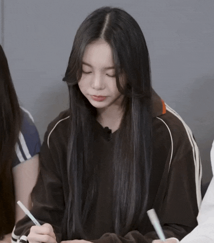a girl with long black hair is holding a pen