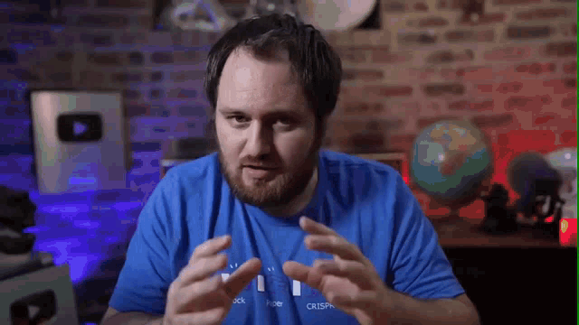 a man with a beard wearing a blue shirt with the word crisp on it