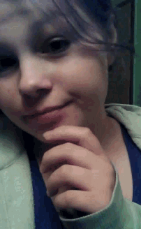 a close up of a girl 's face with a hand on her chin