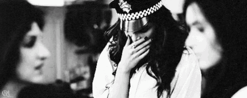 a woman wearing a police hat is covering her mouth with her hand .