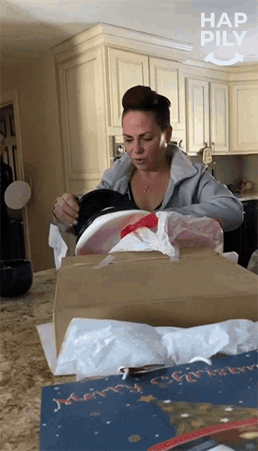 a woman is opening a cardboard box with hap pily written on the bottom