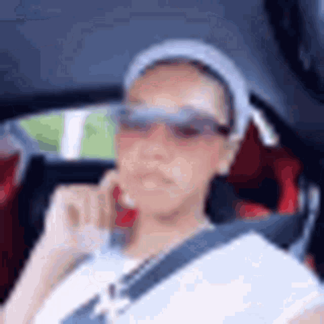 a woman is sitting in a car wearing sunglasses and a headband .