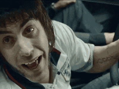 a man with a tattoo on his arm is sitting in a car and smiling .