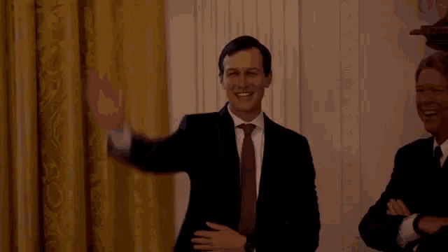 a man in a suit and tie is standing next to another man in a suit and tie .