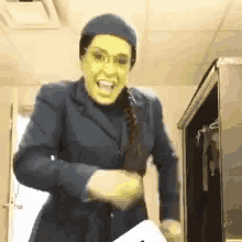 a woman wearing a blue suit and a yellow mask is standing in a room .