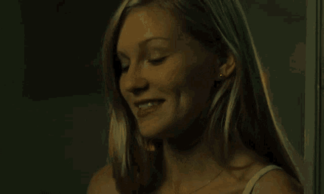 a woman is smiling and smoking a cigarette in a dark room