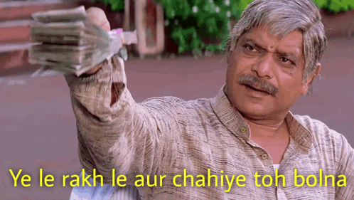 a man is holding a stack of money with the caption ye le rakh le aur chahiye toh bola