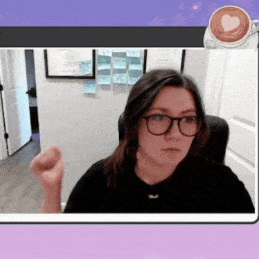 a woman wearing glasses and a black shirt is sitting in front of a wall with sticky notes on it