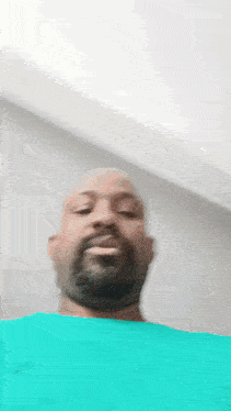 a man with a beard is wearing a green shirt .