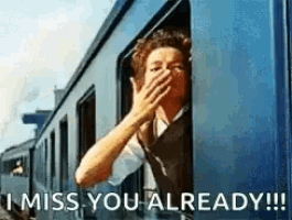 a woman is covering her mouth while looking out of a train window with the words `` i miss you already '' .