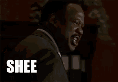 a man in a suit and tie is making a funny face and saying sheeeee .