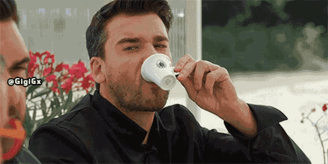 a man drinking a cup of coffee with the hashtag gigigx above him