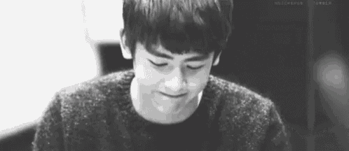 a black and white photo of a young man wearing a sweater and looking down .