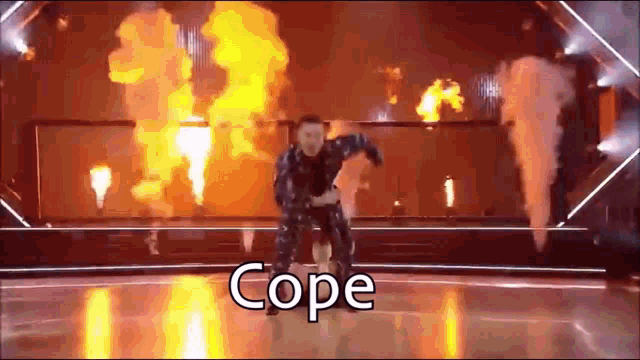 a man is dancing on a stage with fire behind him and the word cope is on the bottom