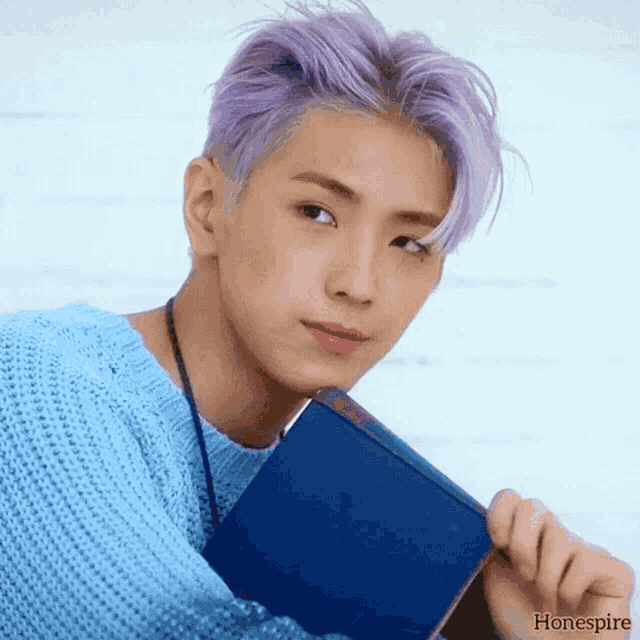 a young man with purple hair is holding a blue book with the word hone spire written on the bottom
