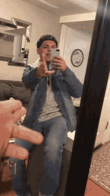 a man in a denim jacket is taking a picture of himself in the mirror