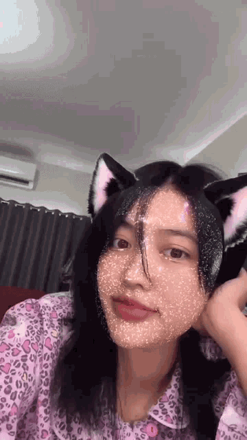 a girl wearing a cat ear headband is looking at the camera