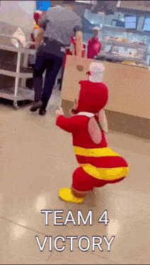 a mascot in a red and yellow outfit with the words team 4 victory written on the bottom