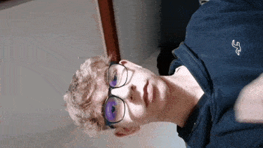 a young man wearing glasses and a blue sweatshirt with the letter a on it