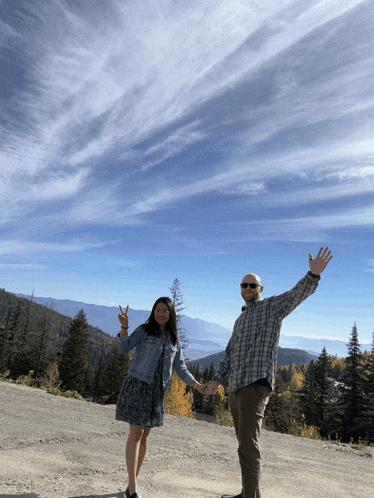 a man and a woman are standing on a dirt road holding hands