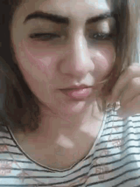 a close up of a woman 's face with her eyes closed and a striped shirt .