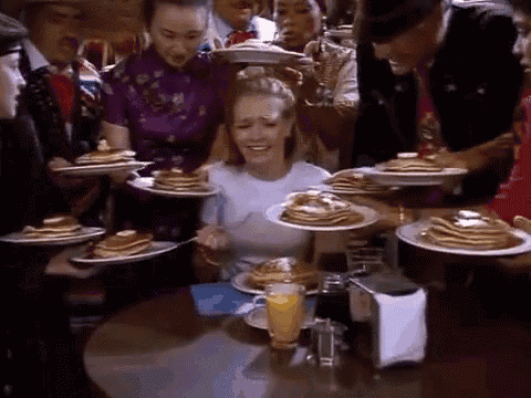 a woman sitting at a table with plates of pancakes on it .