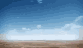 a desert landscape with a blue sky and white clouds in the background .