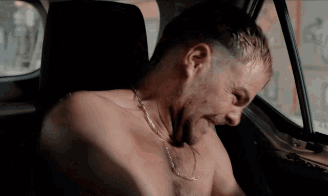 a man without a shirt is sitting in a car