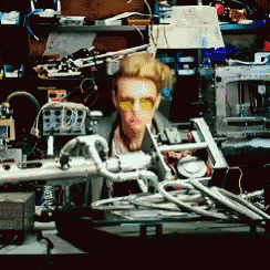 a man wearing yellow glasses is sitting in a messy room