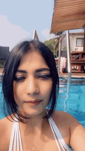 a woman in a bikini is taking a selfie in a pool .
