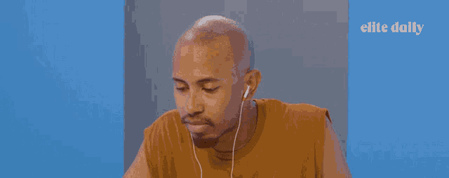 a man wearing ear buds is sitting in front of a blue wall with the words elite daily on it
