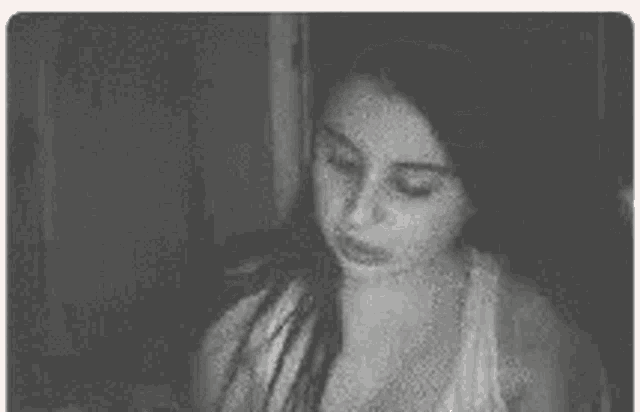 a black and white photo of a woman with long hair in a white tank top .