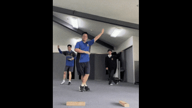 a man in a blue shirt is dancing in a room with other men