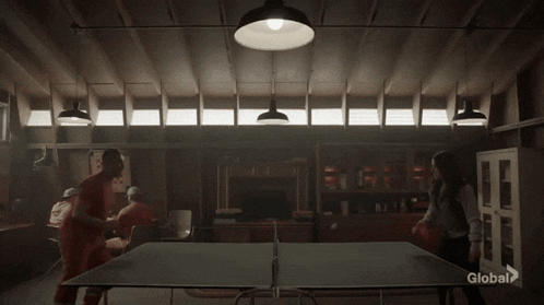 a group of people are playing ping pong in a dark room with a sign that says global on it