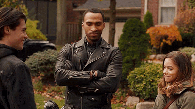 a man in a leather jacket is standing with his arms crossed