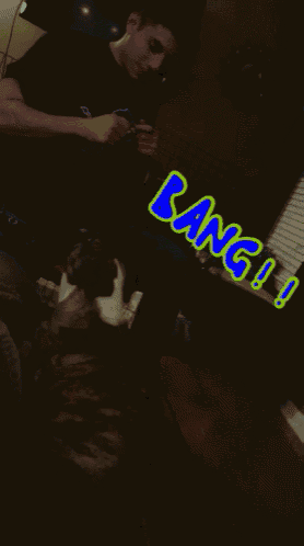 a man in a black shirt with a blue lion on it is sitting on a couch with bang written in green