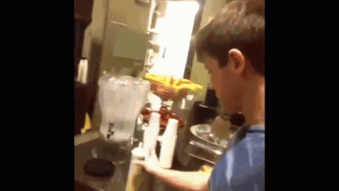a young boy is standing in front of a refrigerator with a pitcher of water .