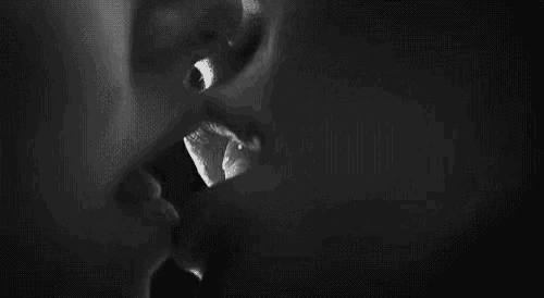 a black and white photo of a man and woman kissing each other .