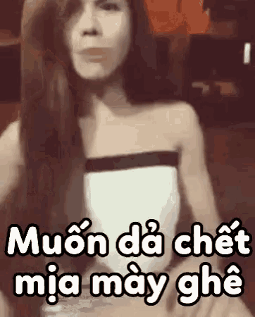 a woman with long hair is standing in front of a sign that says " muon da chet mia may ghe " .