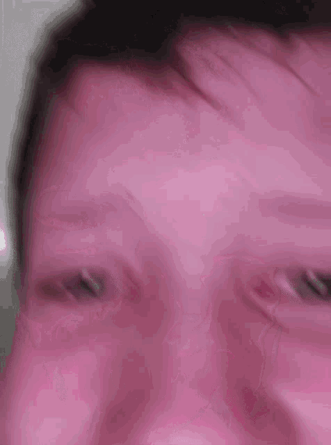 a close up of a young boy 's face with a purple background