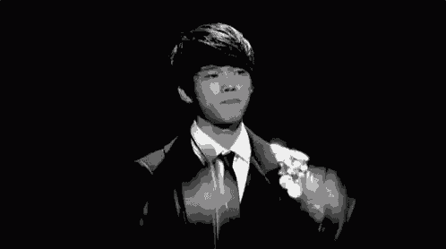 a black and white photo of a man in a suit and tie with hearts coming out of his mouth .