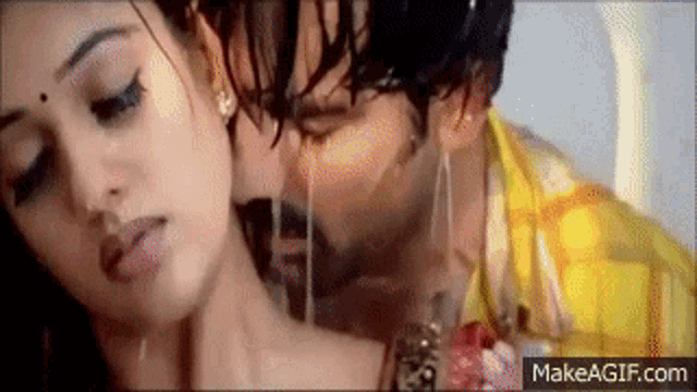 a man and a woman are kissing in the rain and the man is pouring water on the woman 's neck .