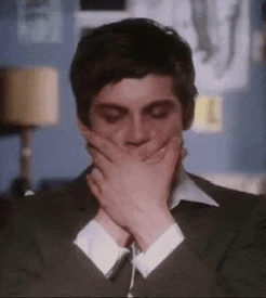 a close up of a man covering his mouth with his hands .