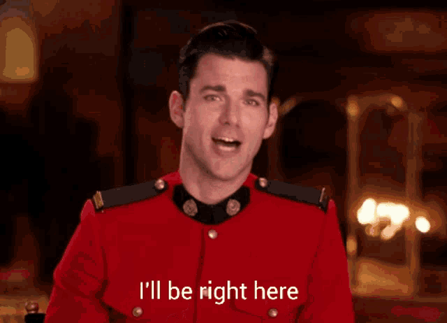 a man in a red uniform says " i 'll be right here " with his finger