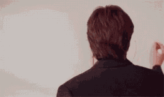 a man is standing in front of a white board with the word fuck written in red marker .