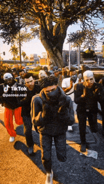 a group of people are walking down a street with a tree in the background and a tiktok logo on the bottom right